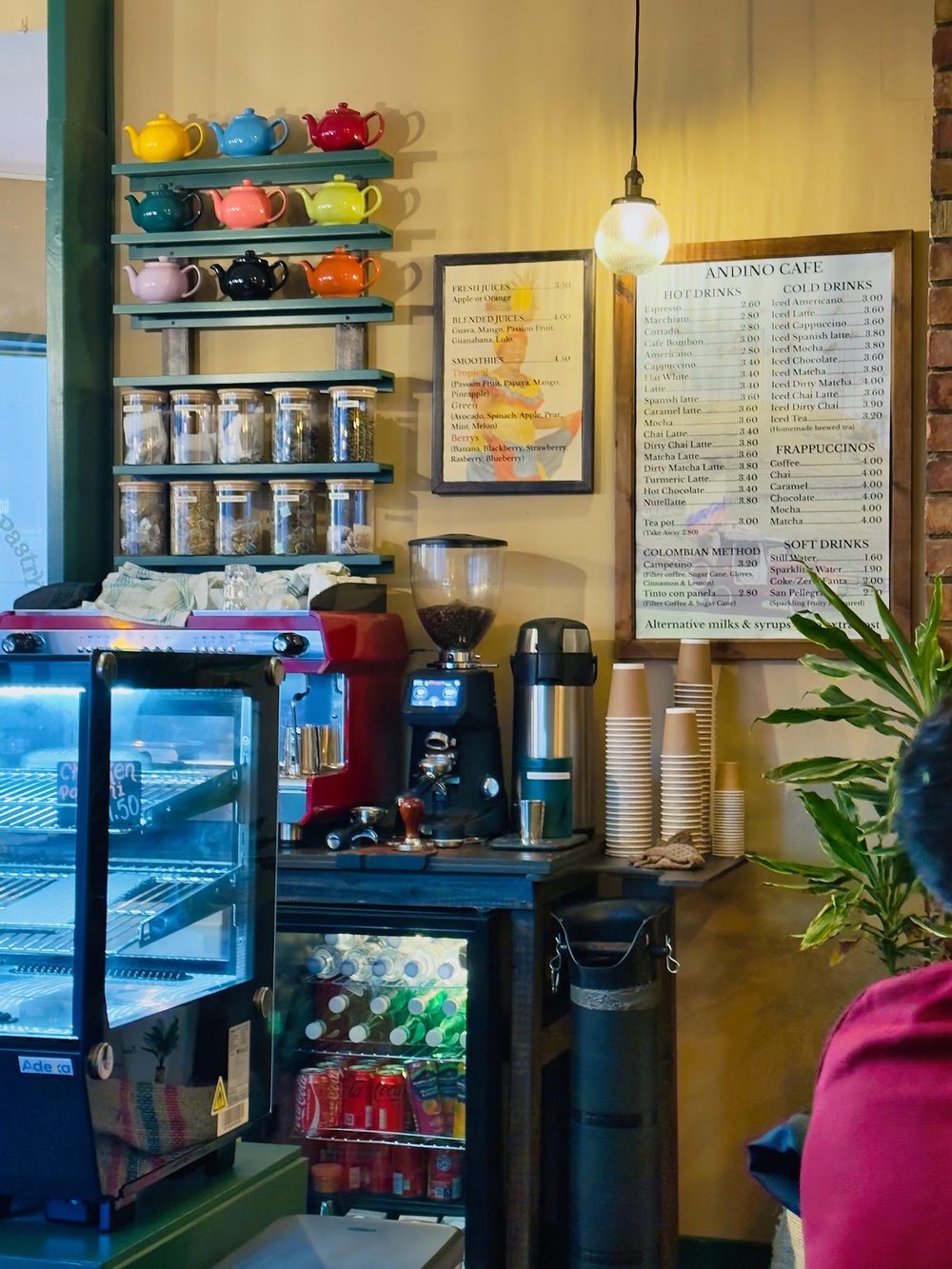 The service counter with the coffee machine, drinks fridge and shelves of jars