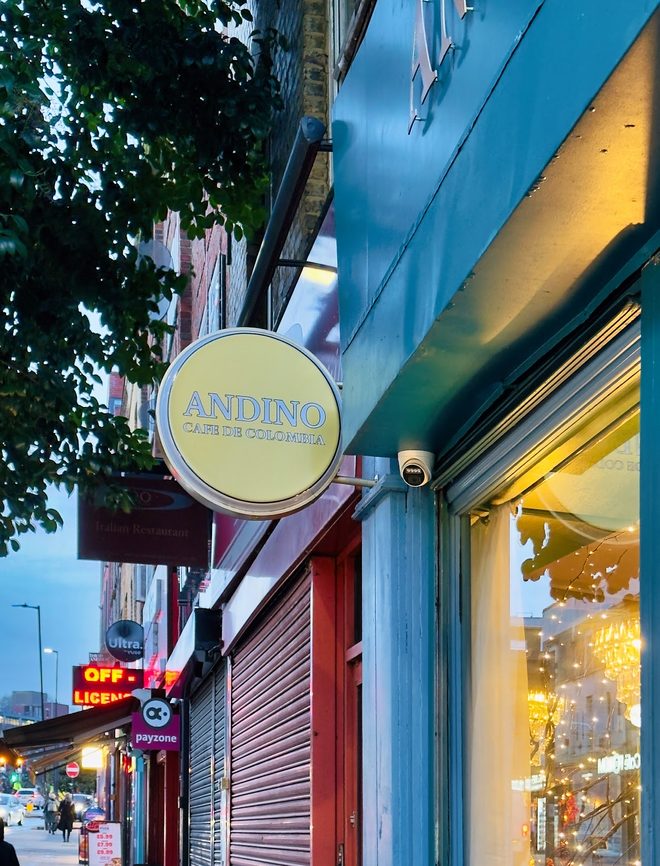 The Andino shopfront at dusk with the sign lit and warm window light down the street
