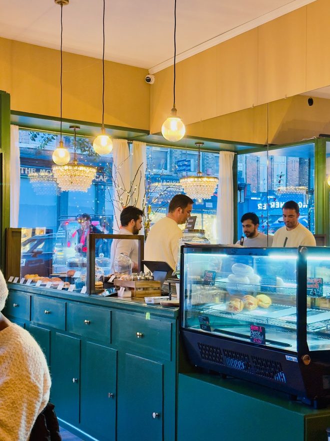Staff working behind the pastry display at the teal counter