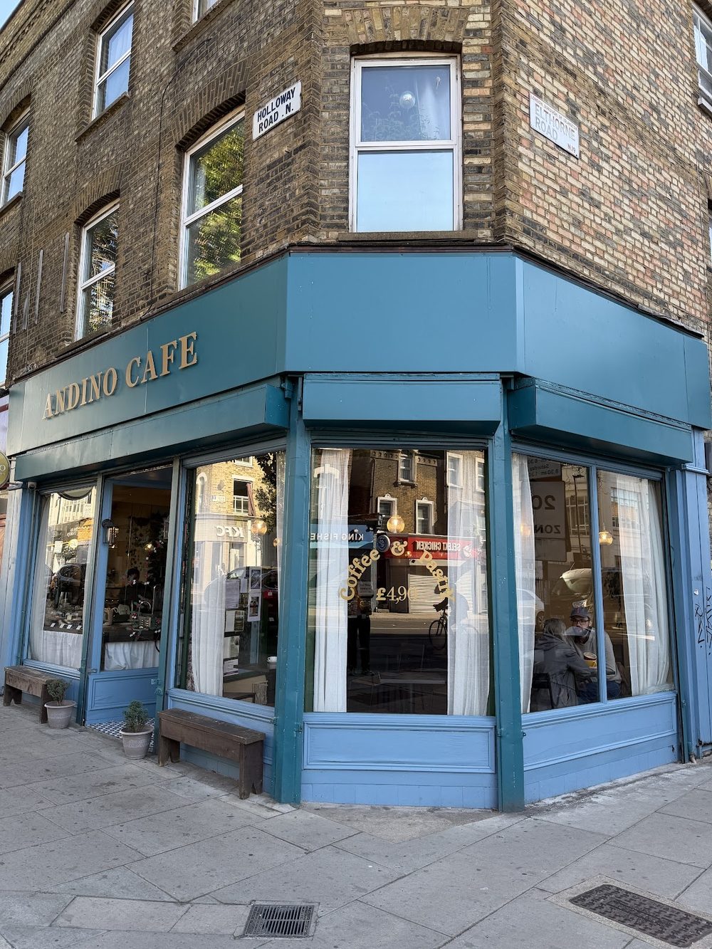 The blue-painted corner shopfront of Andino Cafe in daylight on Holloway Road
