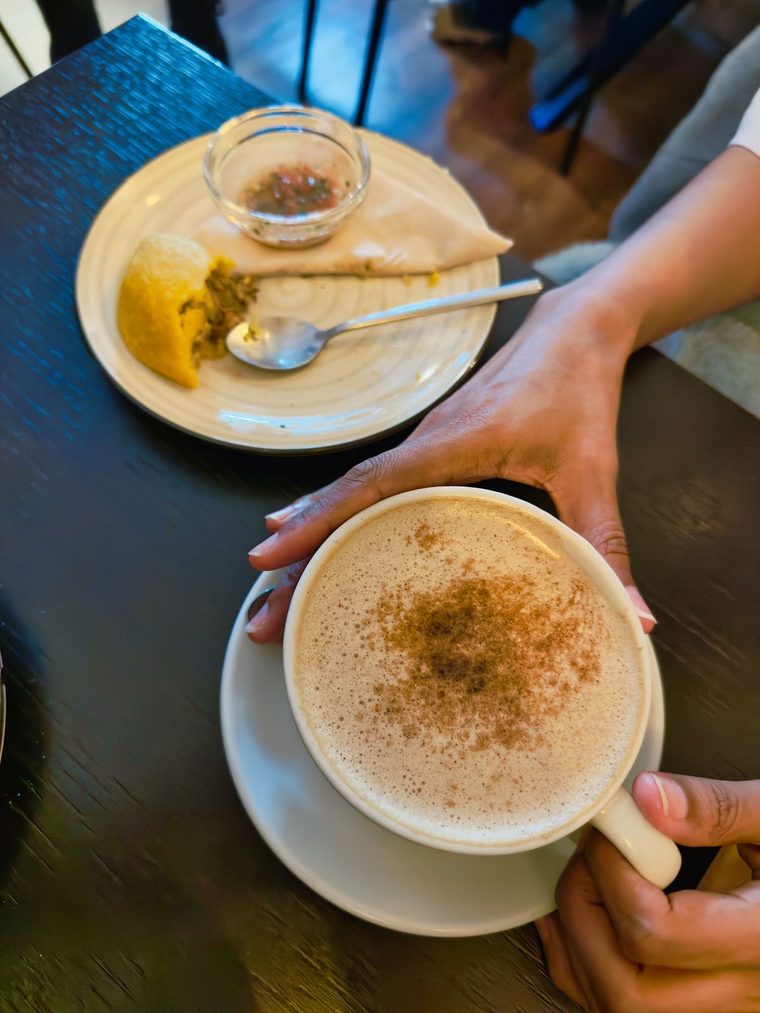 A cinnamon-dusted cappuccino held in one hand