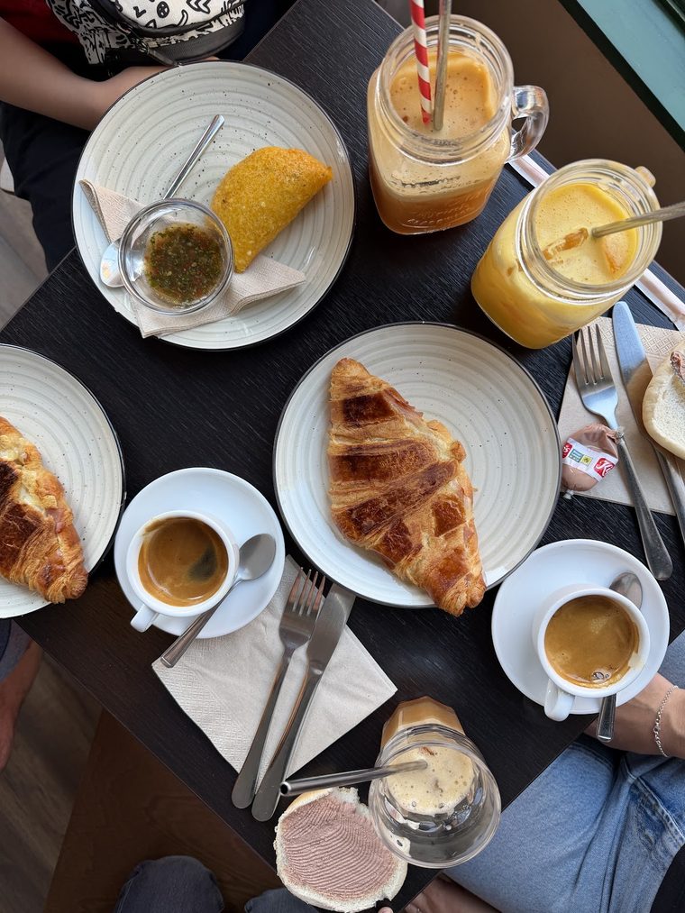 Espressos, croissant, empanada and iced drinks across a table