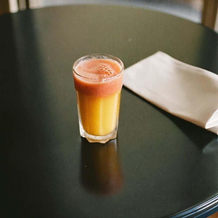 A tall glass of fresh juice on a dark cafe table