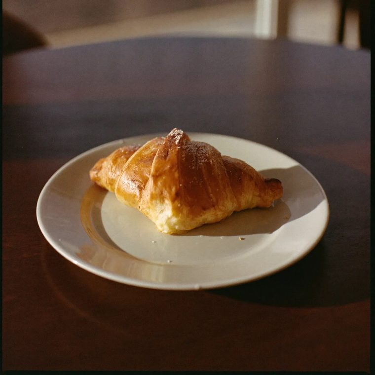 A croissant on a plate on a dark cafe table